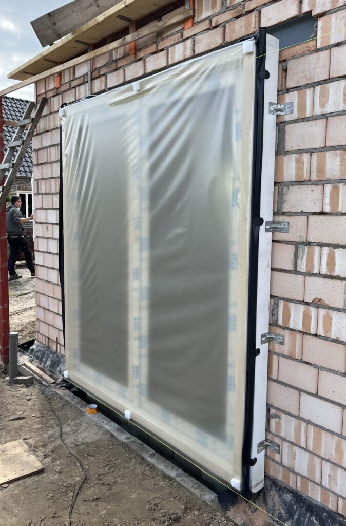 Een prefab-pui die nog in het plastic zit, maar wel al op de bouwplaats in een bakstenen bouwwerk gemonteerd is.